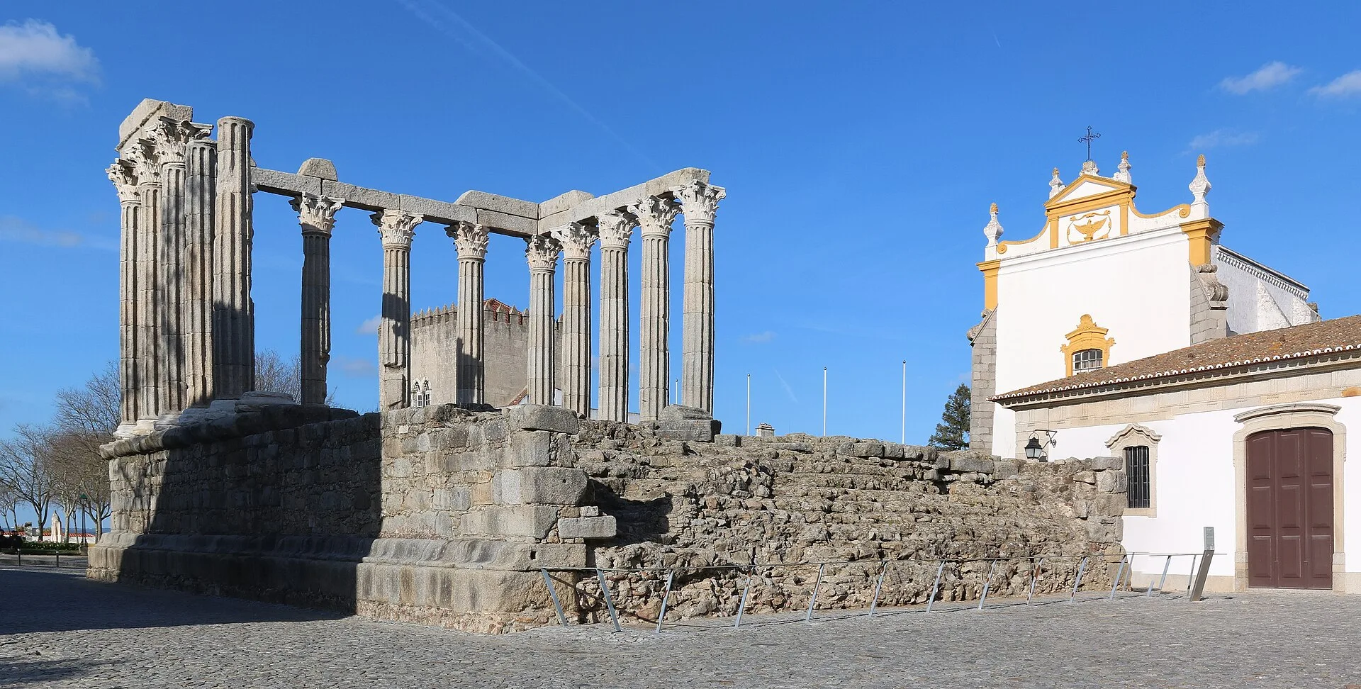 The Roman Temple of Evora (Temple of Diana) with its Corinthian columns standing on a stone podium under a clear blue sky, Evora, Portugal