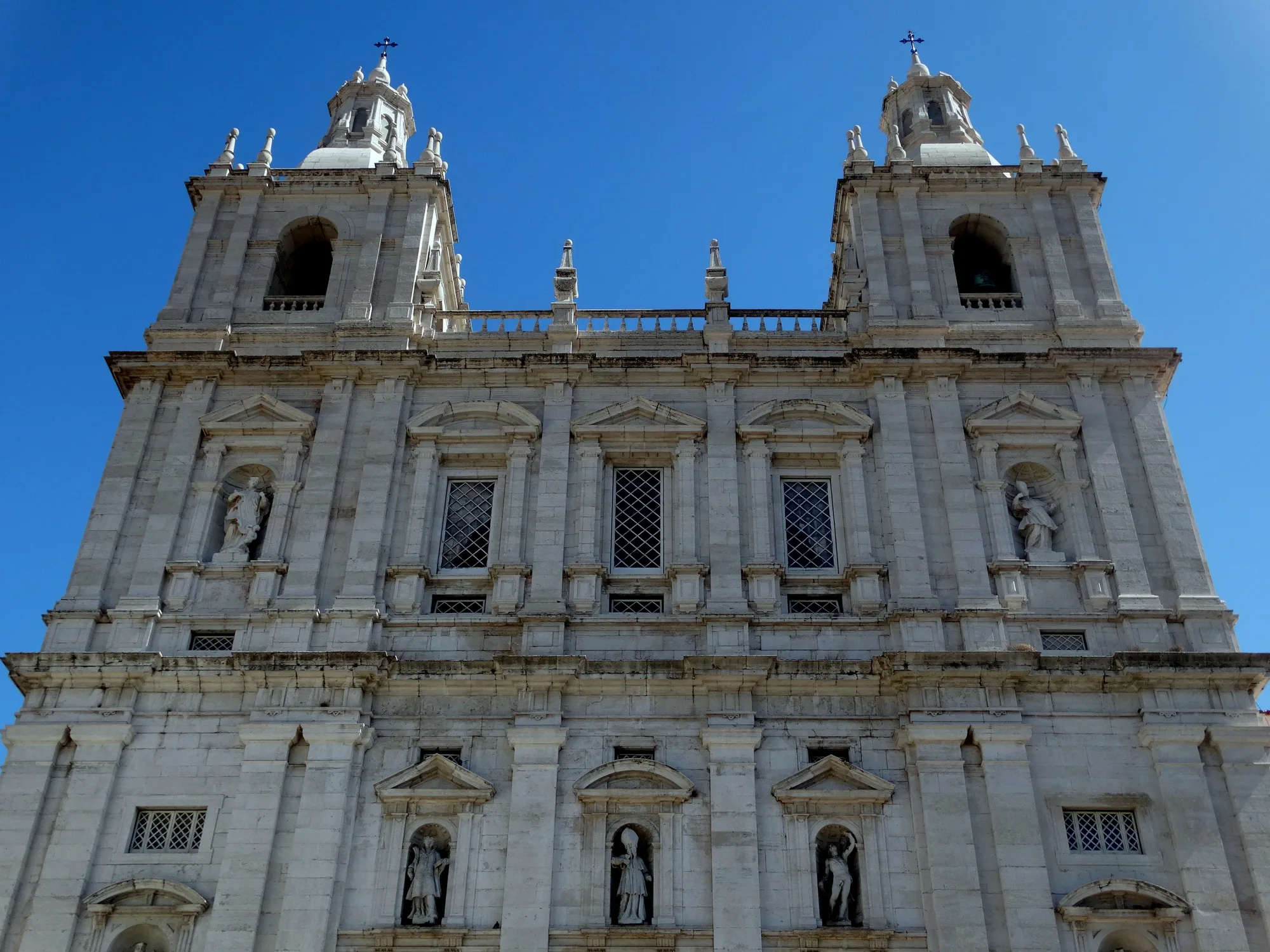 White twin-towered Mannerist facade of the Monastery of São Vicente de Fora in Lisbon against a clear blue sky