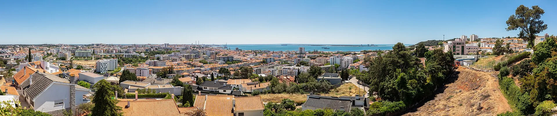 Panorama of the city of Setubal with red-tiled rooftops descending to the blue Sado estuary, the port and the Troia spit beyond, Portugal